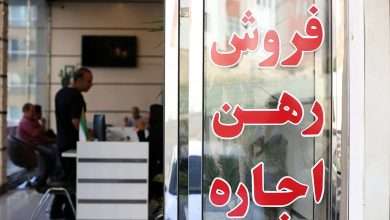 یک مرد داخل یک بنگاه معاملات املاک در حال پرس و جو است. روی شیشه بنگاه نوشته است: فروش، رهن، اجاره