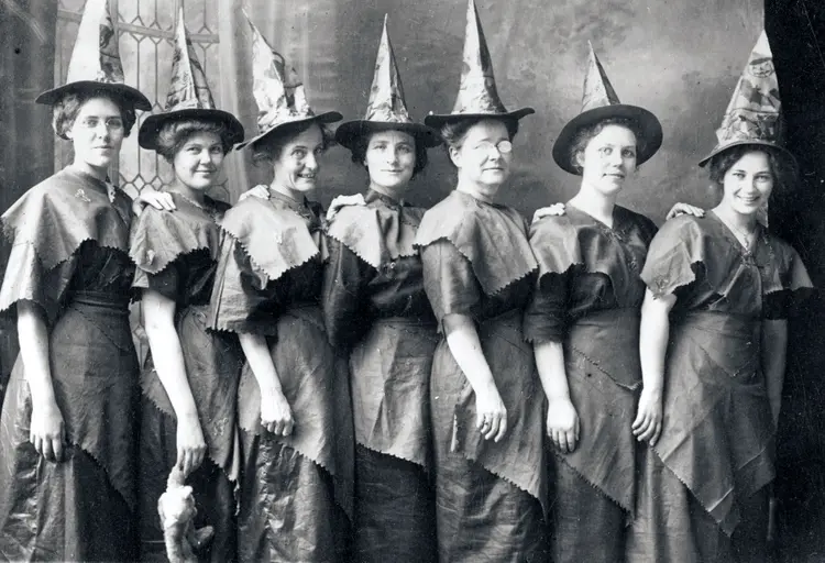 7 زن با لباس و کلاه به شکل جادوگران ژست گرفته اند.
