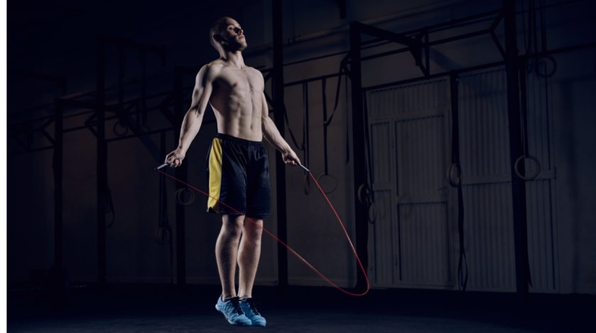 یک مرد با شورت ورزشی و کتانی در حال طناب زدن