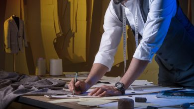 یک خیاط جوان روی میز کار خود خم شده و در حال کار کردن است.